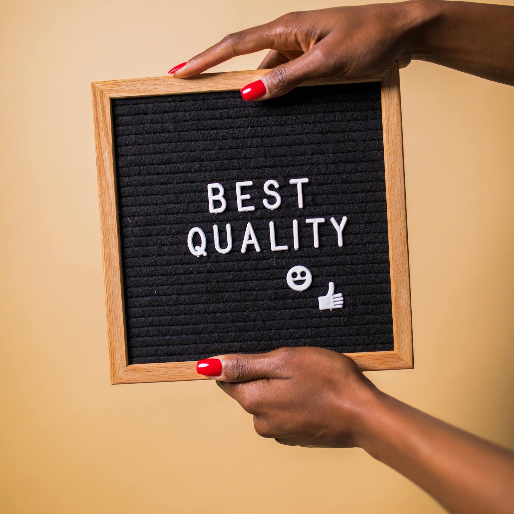 Hands holding a letter board with 'Best Quality' text, emoji, and thumbs up.